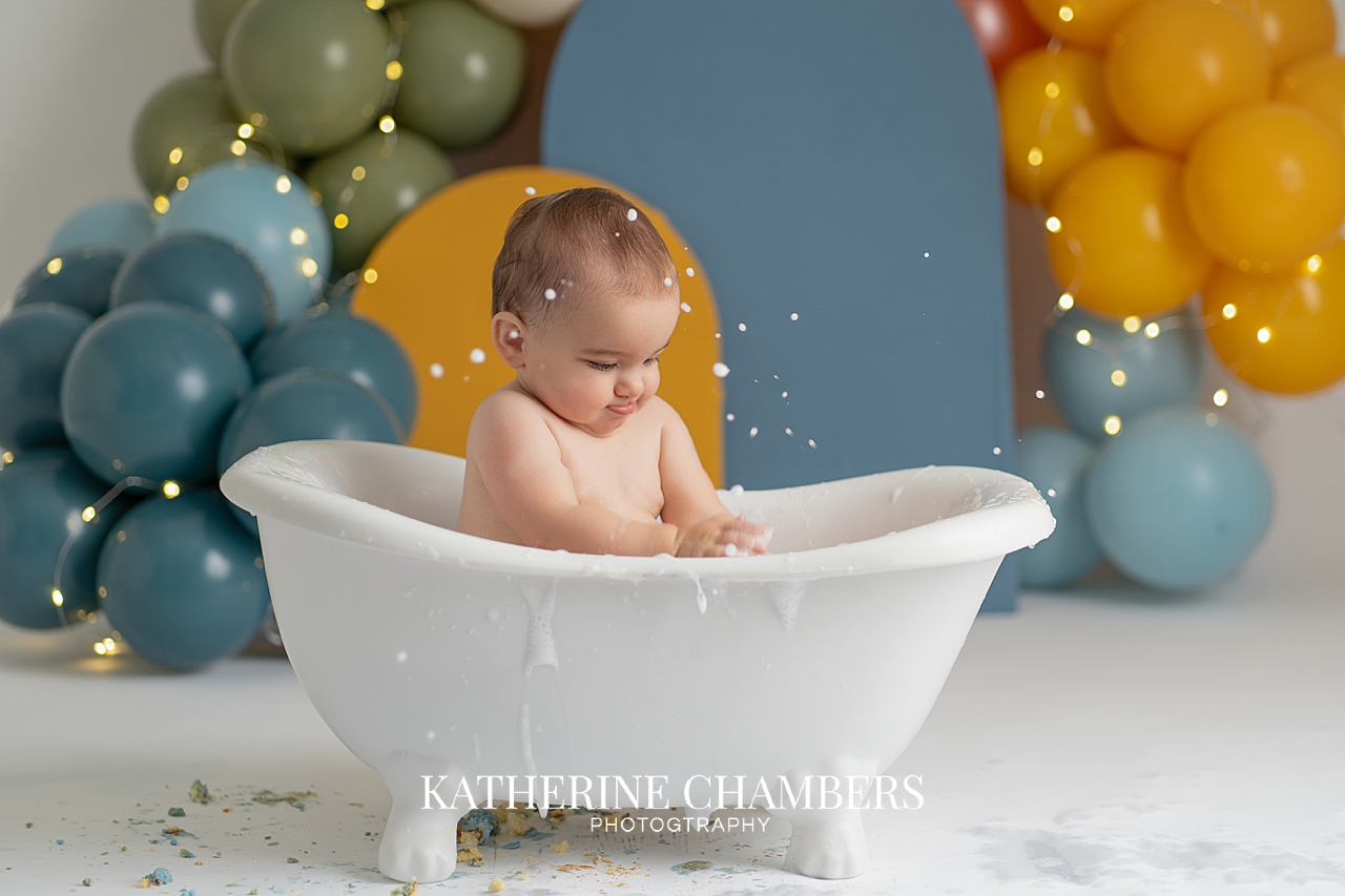 Elijah enjoying his bath splash with messy hands and face during his first birthday session in Cleveland