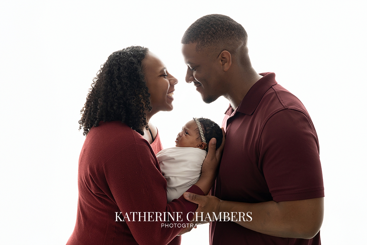 ew parents holding newborn baby girl during studio newborn session