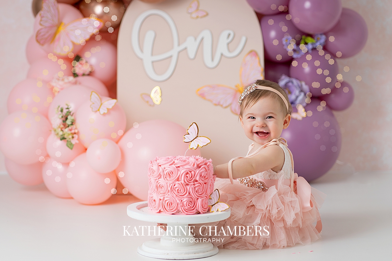Baby girl smiling during butterfly cake smash session