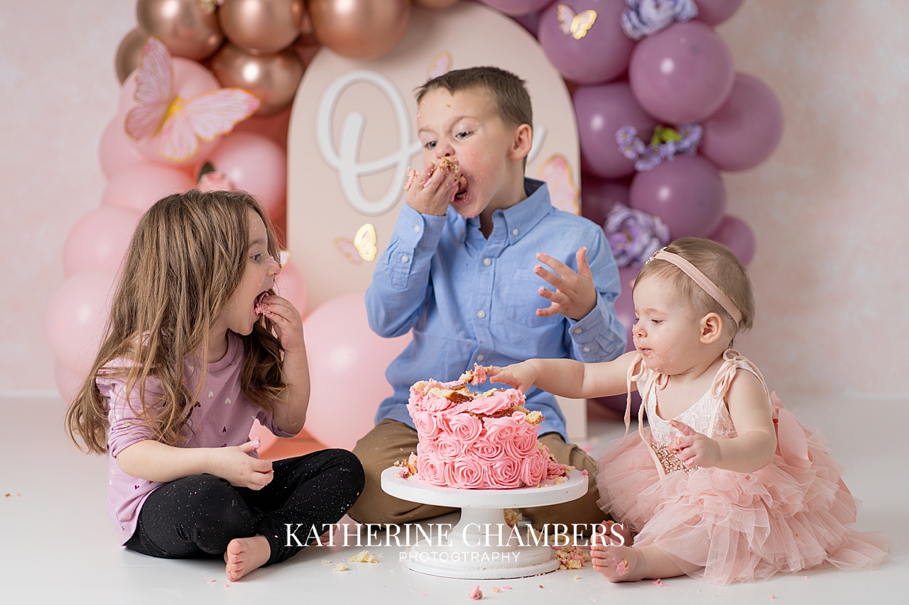 Siblings eating cake at one year session