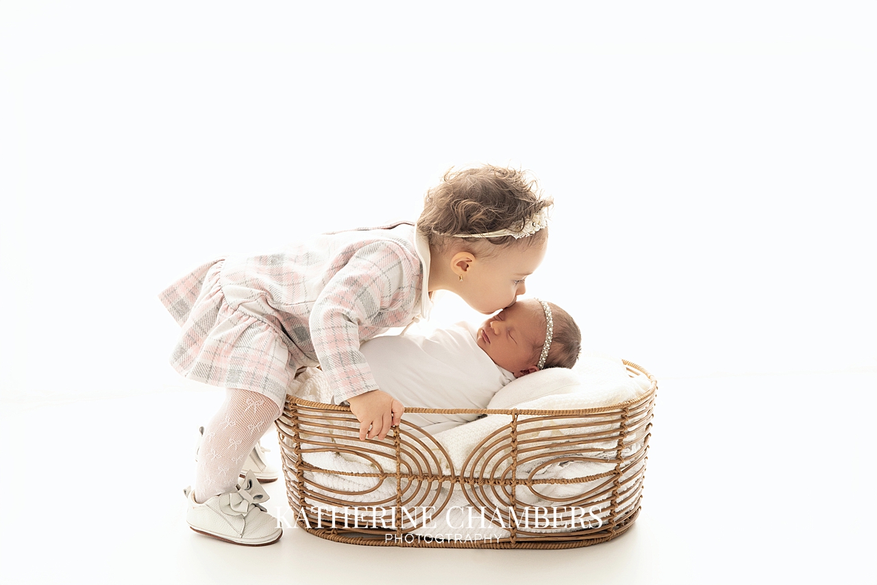 Big sister kissing her newborn baby sister