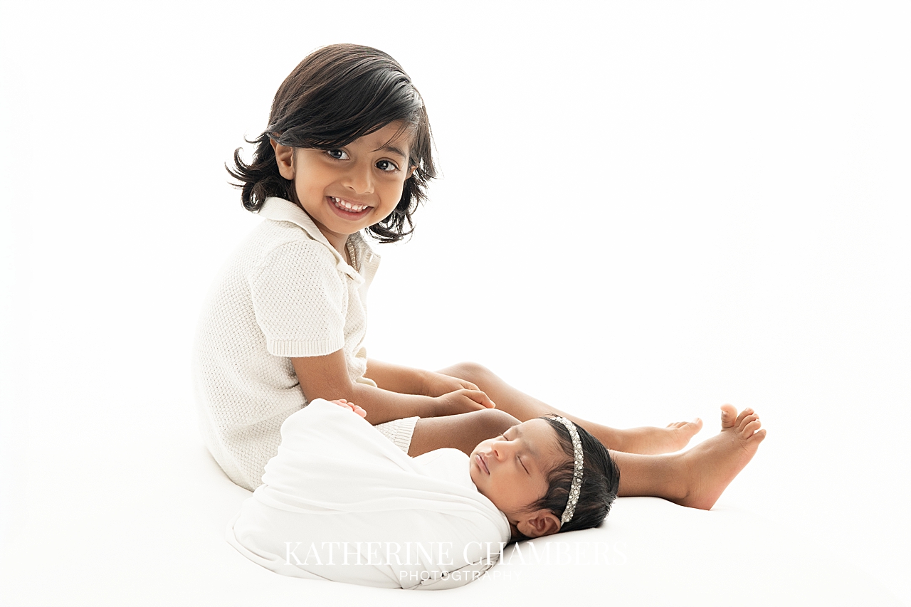 Big brother sitting with his baby sister Asha during newborn family photos.