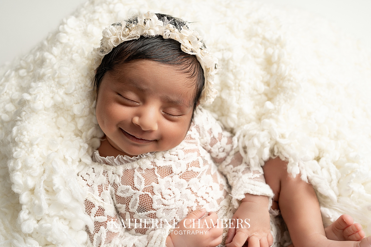 Newborn baby girl Asha smiling during her photography session.