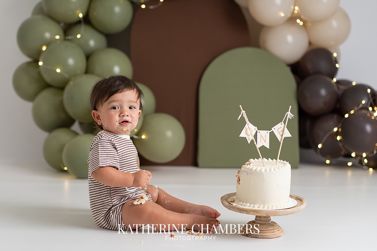 EJ’s brown and green first birthday cake smash setup