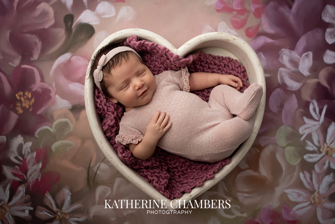 Newborn baby girl in heart bowl